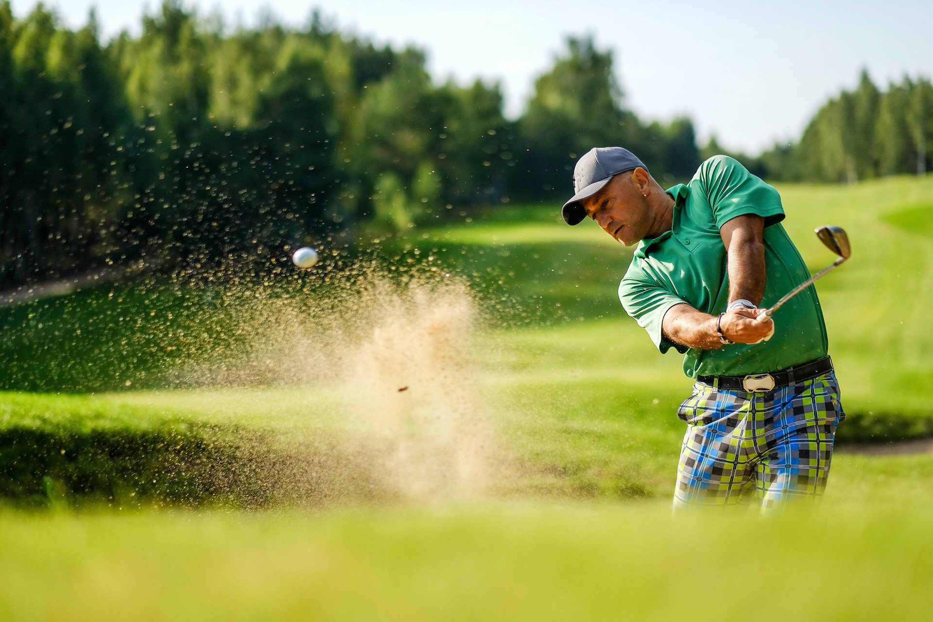 Golfer hits ball from a bunker with golf club