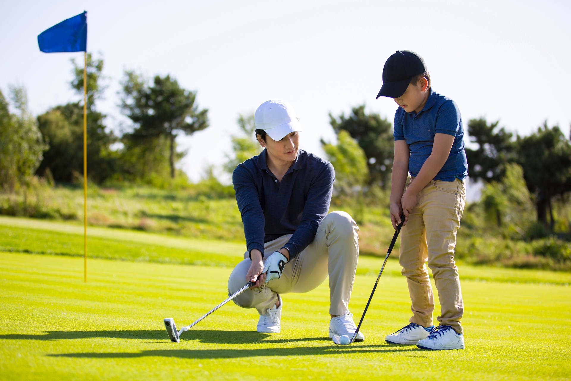 Father and son practicing hole-in-one golf or tee shots on a sunny golf course, coach and student, encouragement and praise - stock photo